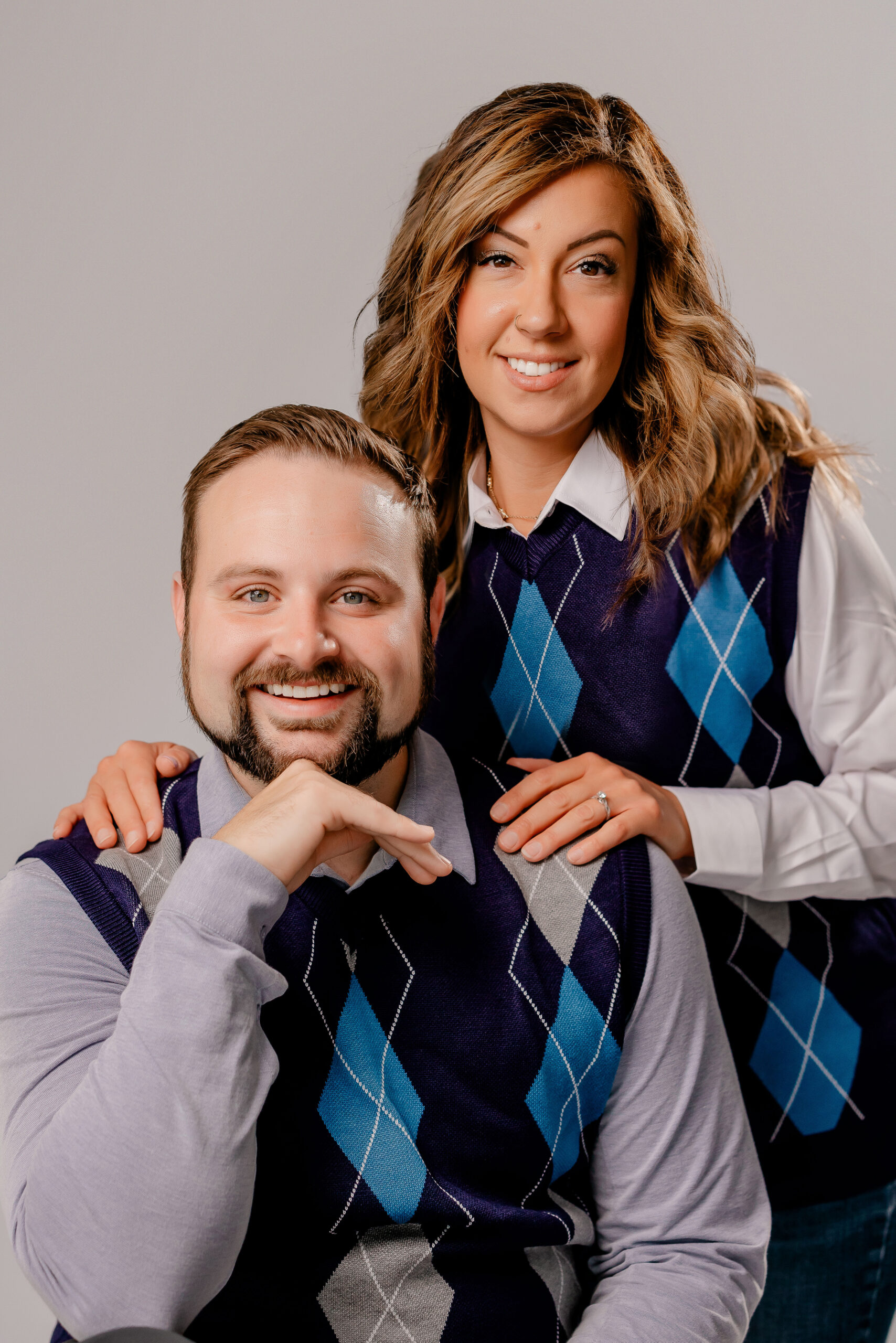 Austin Moore and Ashley Milton wearing matching argyle sweaters in a playful team portrait.