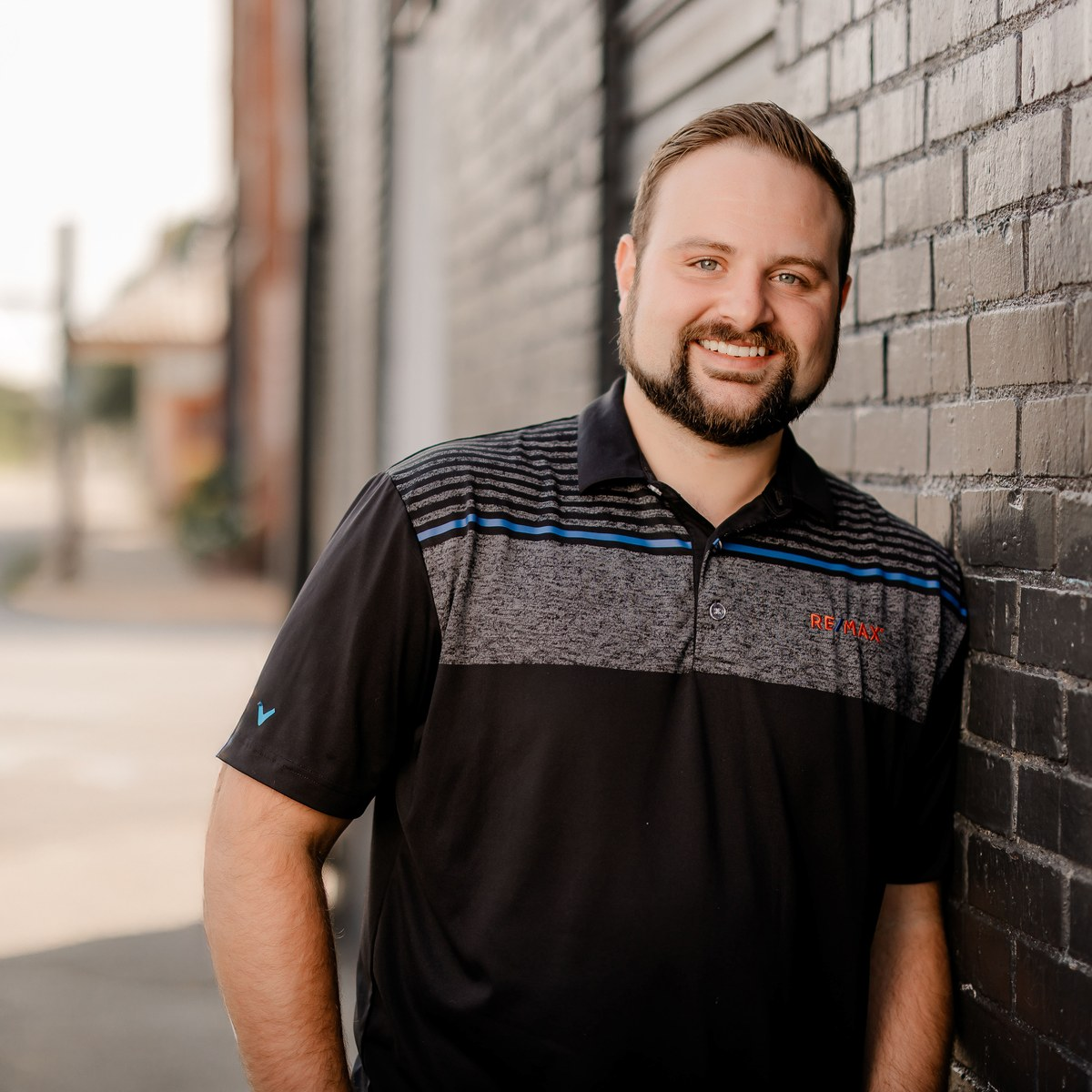 Austin Moore standing beside a dark brick wall